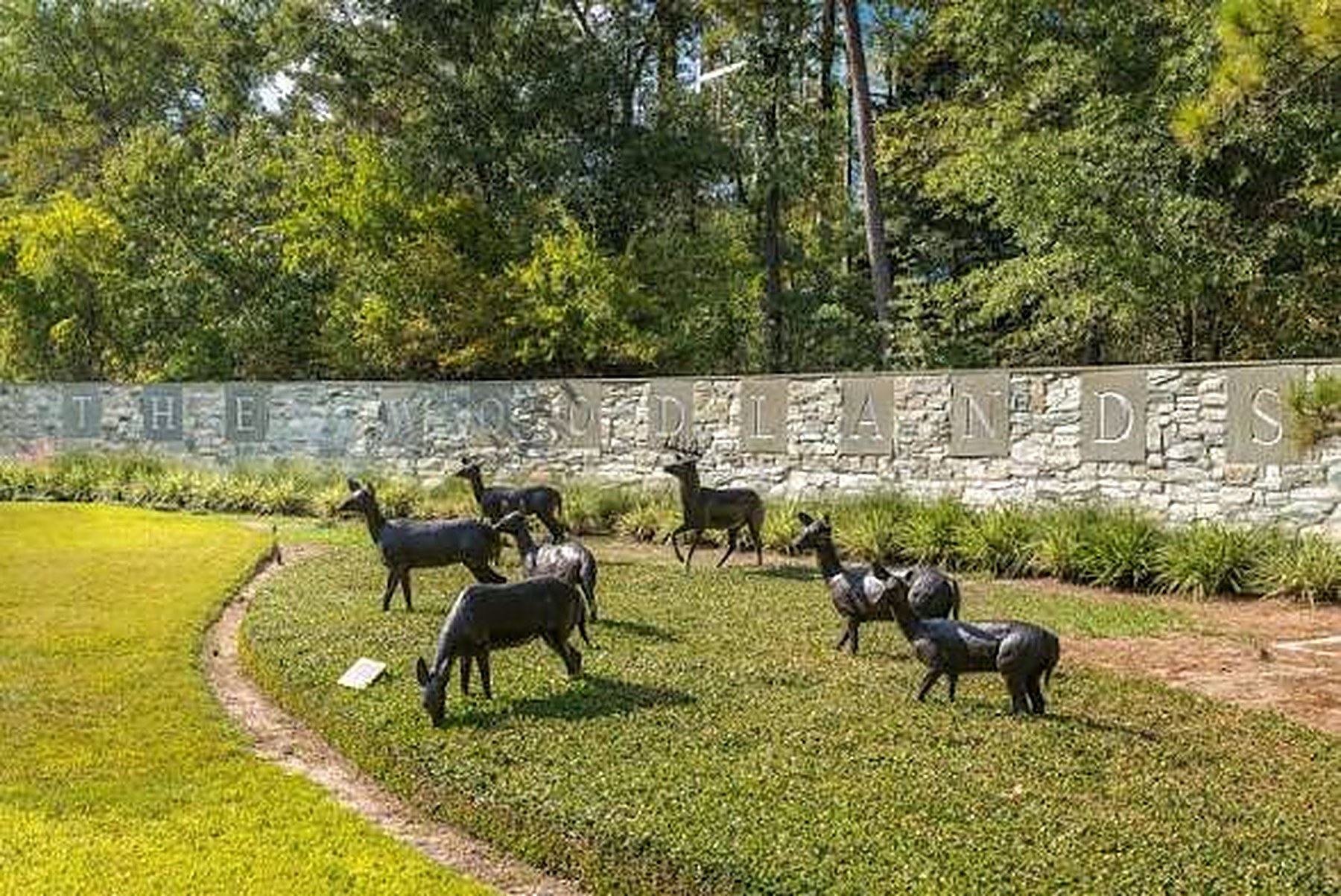 Bronze deer statues on a green lawn at The Woodlands entrance