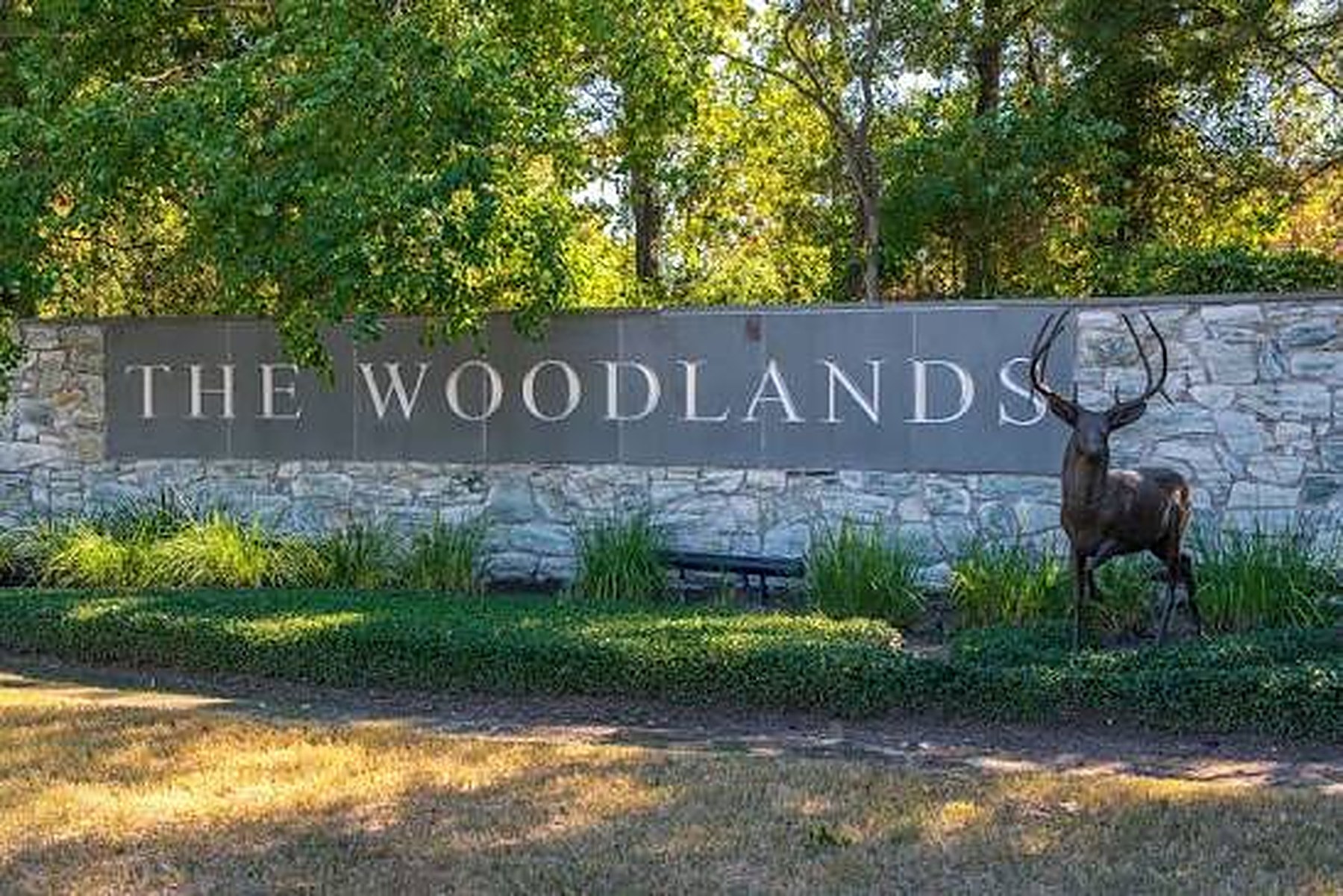 The Woodlands stone sign with a bronze stag statue